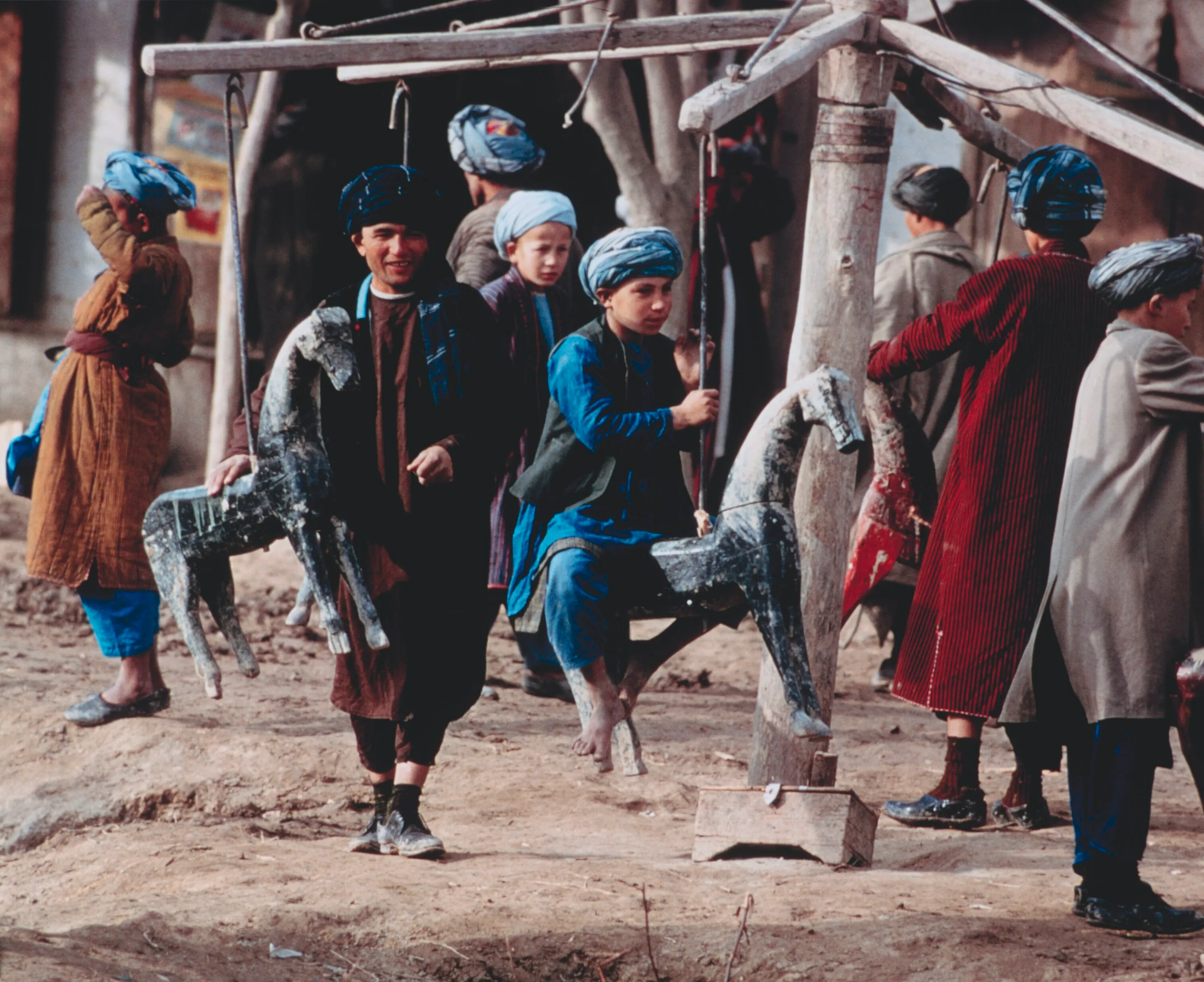Children in chapan coats riding a carved wooden carousel at the Eid al-Fitr festival in Aqcha, Jowzjan, 1967
