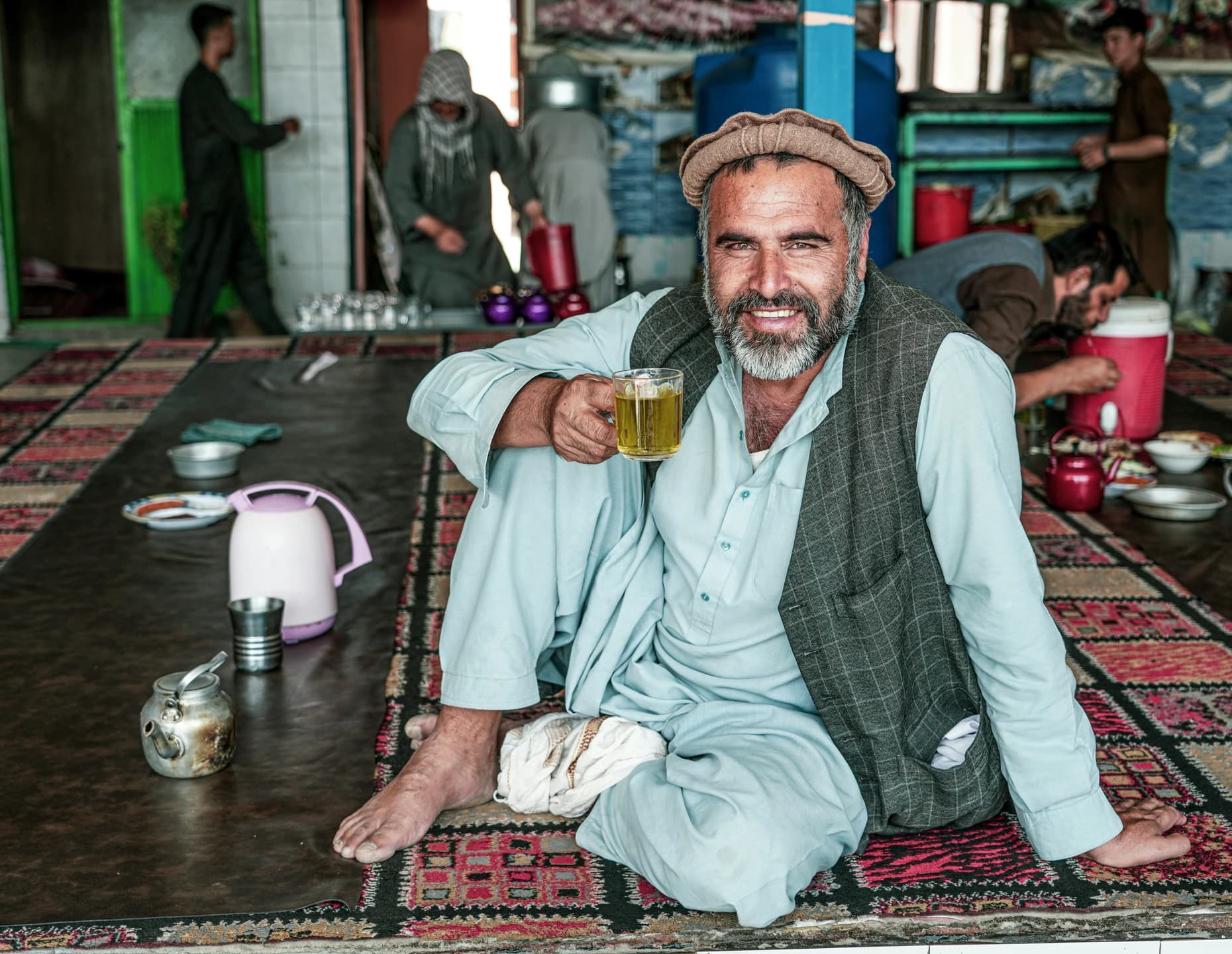 An older Afghan man holding a glass of tea in Kabul