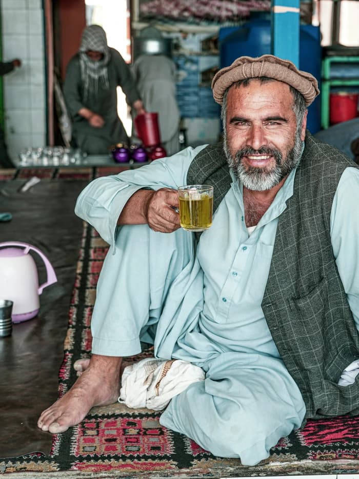 An Afghan man holding a glass of tea