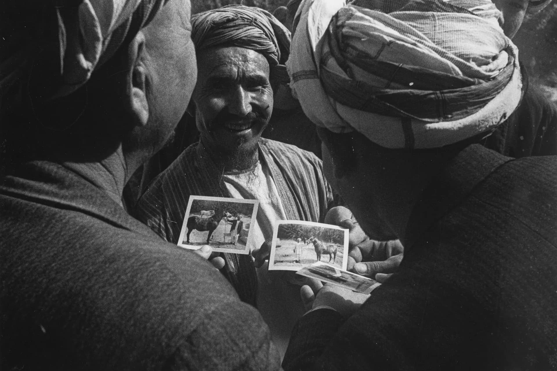 Men sharing photographs in Aqcha, Jowzjan, 1968