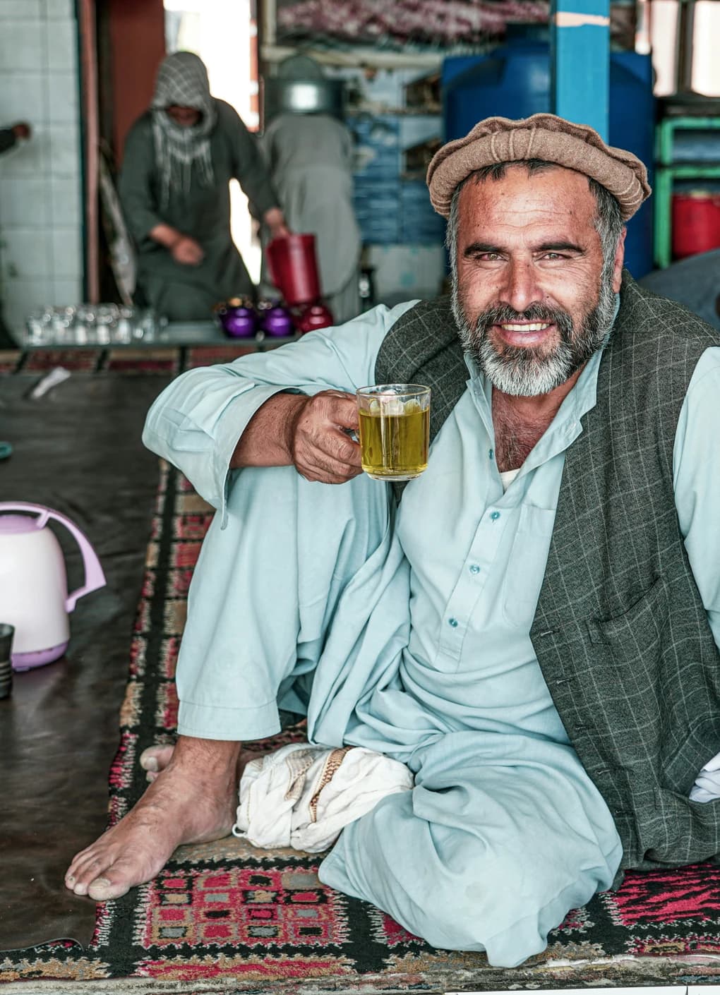 An Afghan man offering a glass of tea