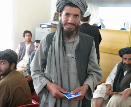 A man in a turban, long shirt and waistcoat at an office in Lashkar Gah, Helmand