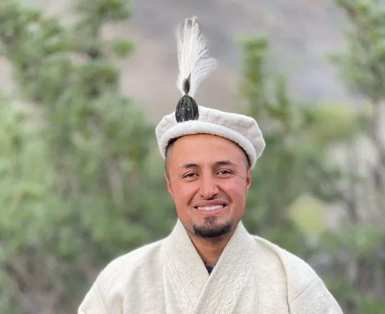 A Wakhi man in a white embroidered robe and a cap with a feather, traditional Wakhi men’s dress
