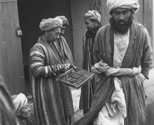 Men in striped chapan coats at the carpet market in Aqcha, 1968