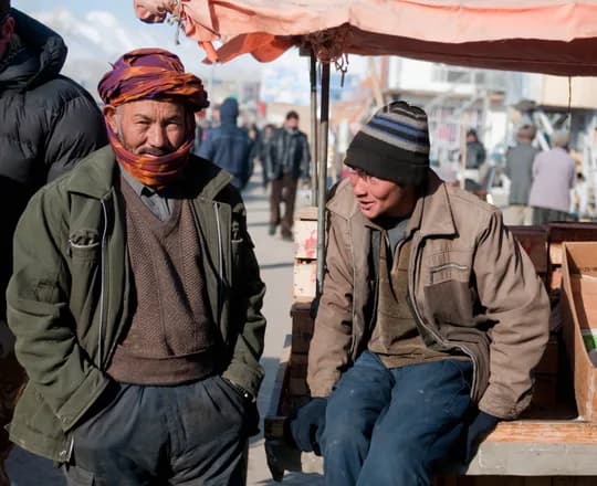 Merchants in warm layers, caps and a wrapped turban at the bazaar in Bamyan