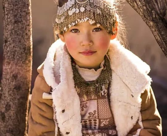 A Hazara girl in a sheepskin-lined coat and a coin-decorated embroidered cap