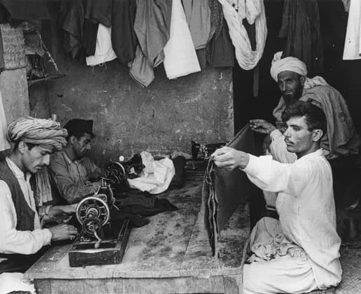 Tailors cutting and sewing clothes at a workshop in Kabul, photographed by Herbert Maeder in 1967