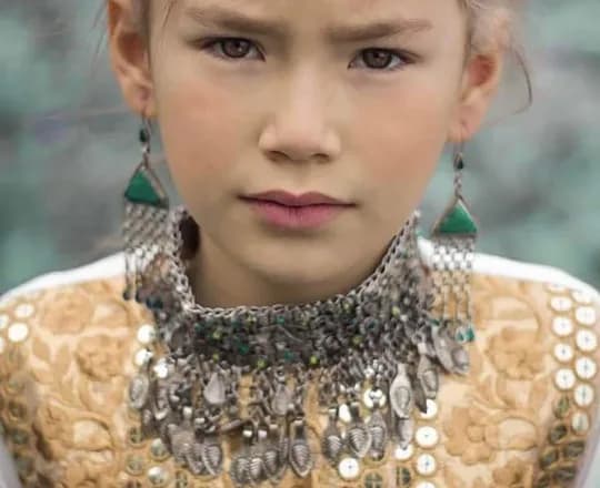 A Hazara girl wearing an embroidered dress with a silver necklace and earrings