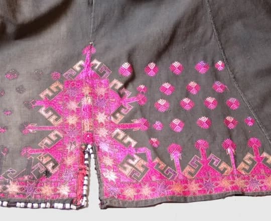 Pink and white embroidery on a black cotton Pashai shirt in the collection of the MAS museum, Antwerp
