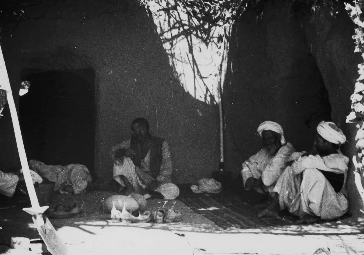 Men seated in the shade in front of a house in Andkhoy, Faryab, 1939–1940