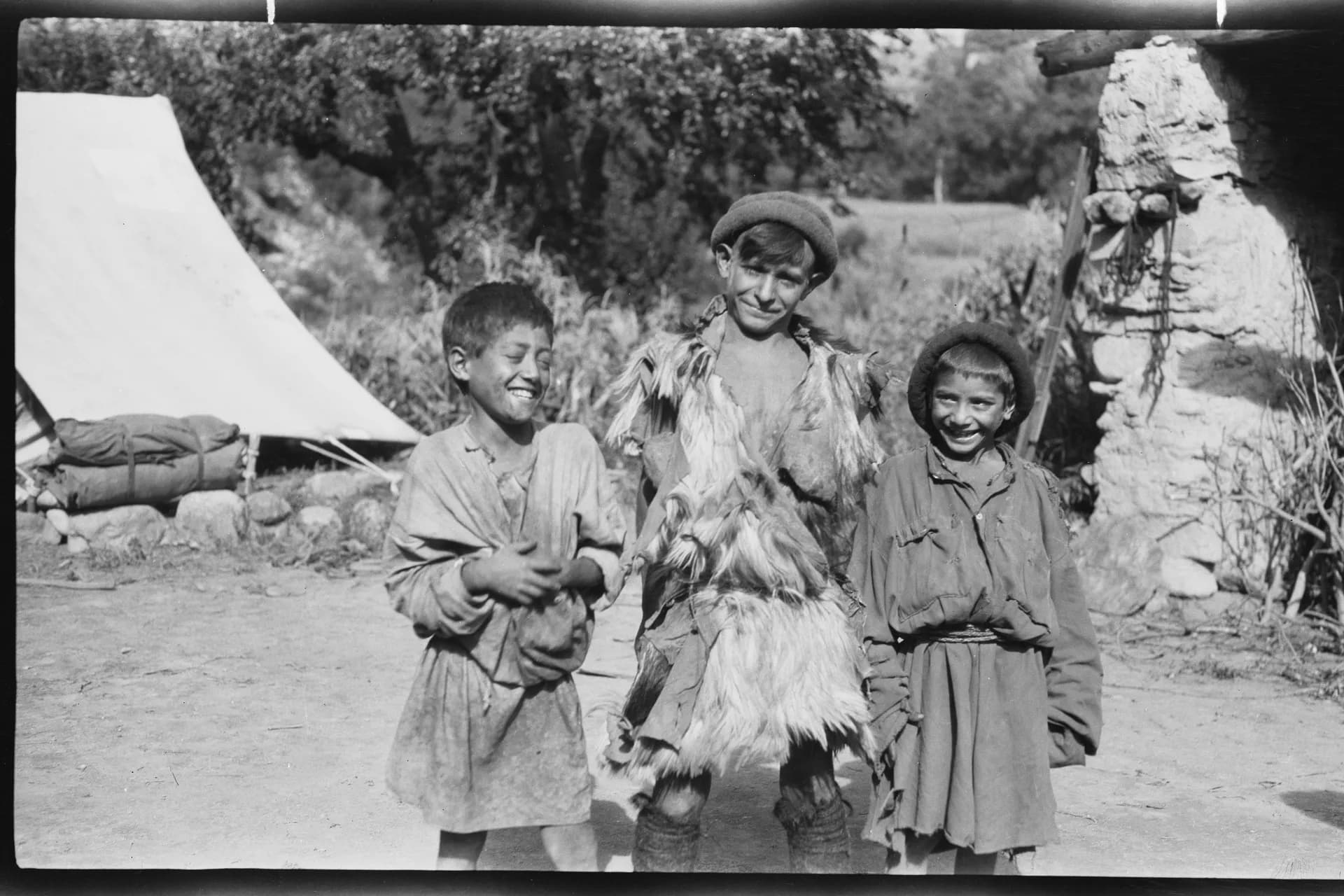 Three laughing Kati boys, one dressed in a goat skin, photographed by linguist Georg Morgenstierne in Urtsun, Chitral, 1929
