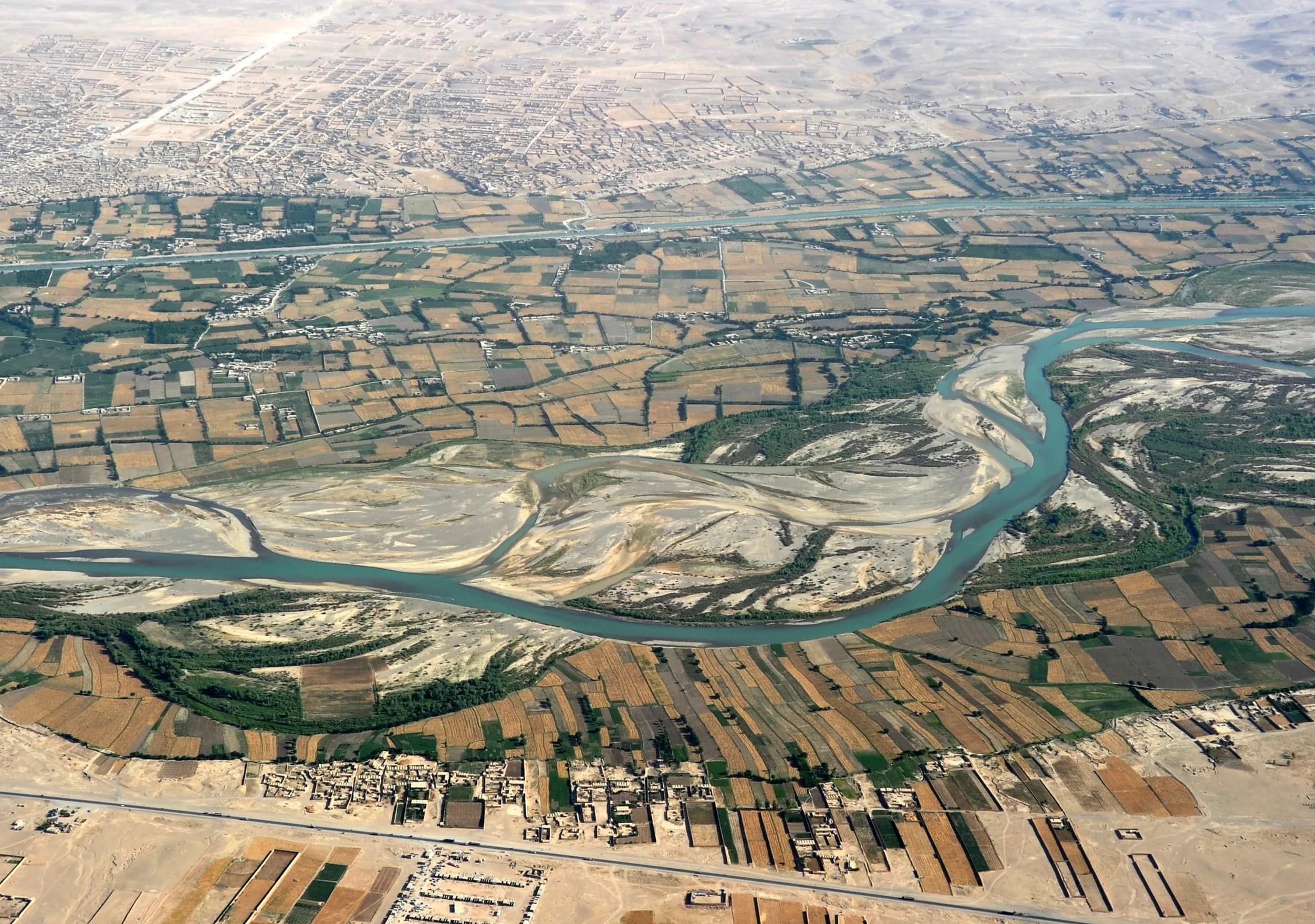 The Helmand River braiding through green farmland near Gereshk, Helmand, seen from the air