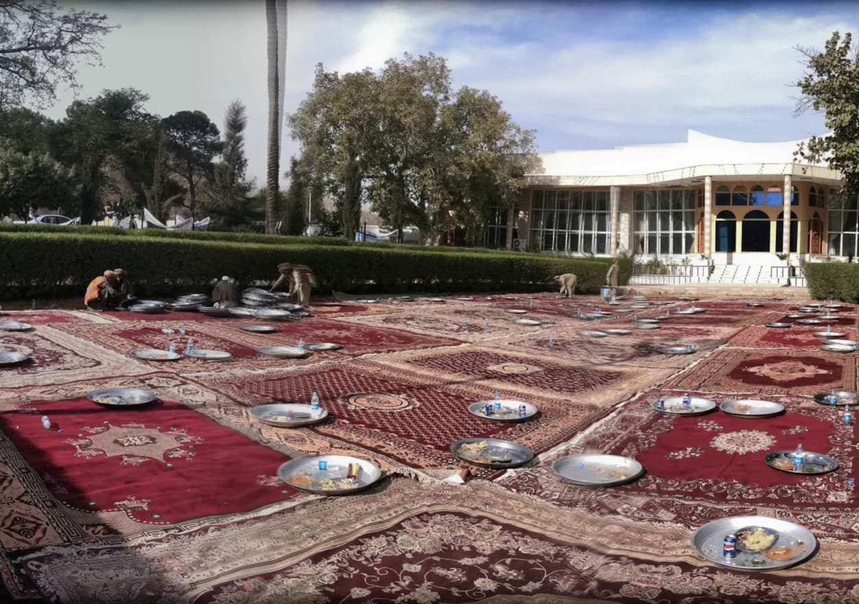 An outdoor meal shared on carpets in Jalalabad