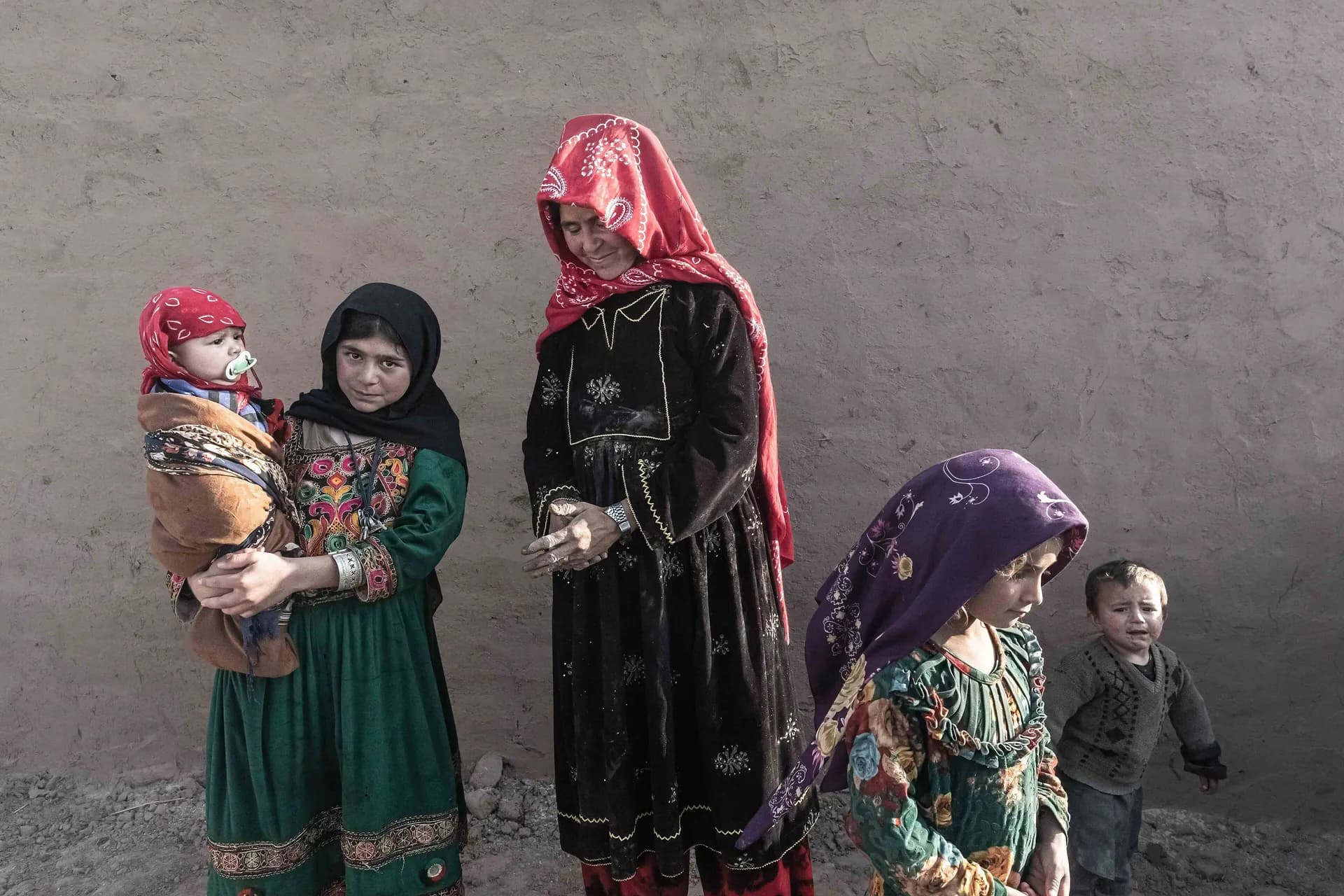 A Tajik woman in Afghanistan with children in colorful traditional dress