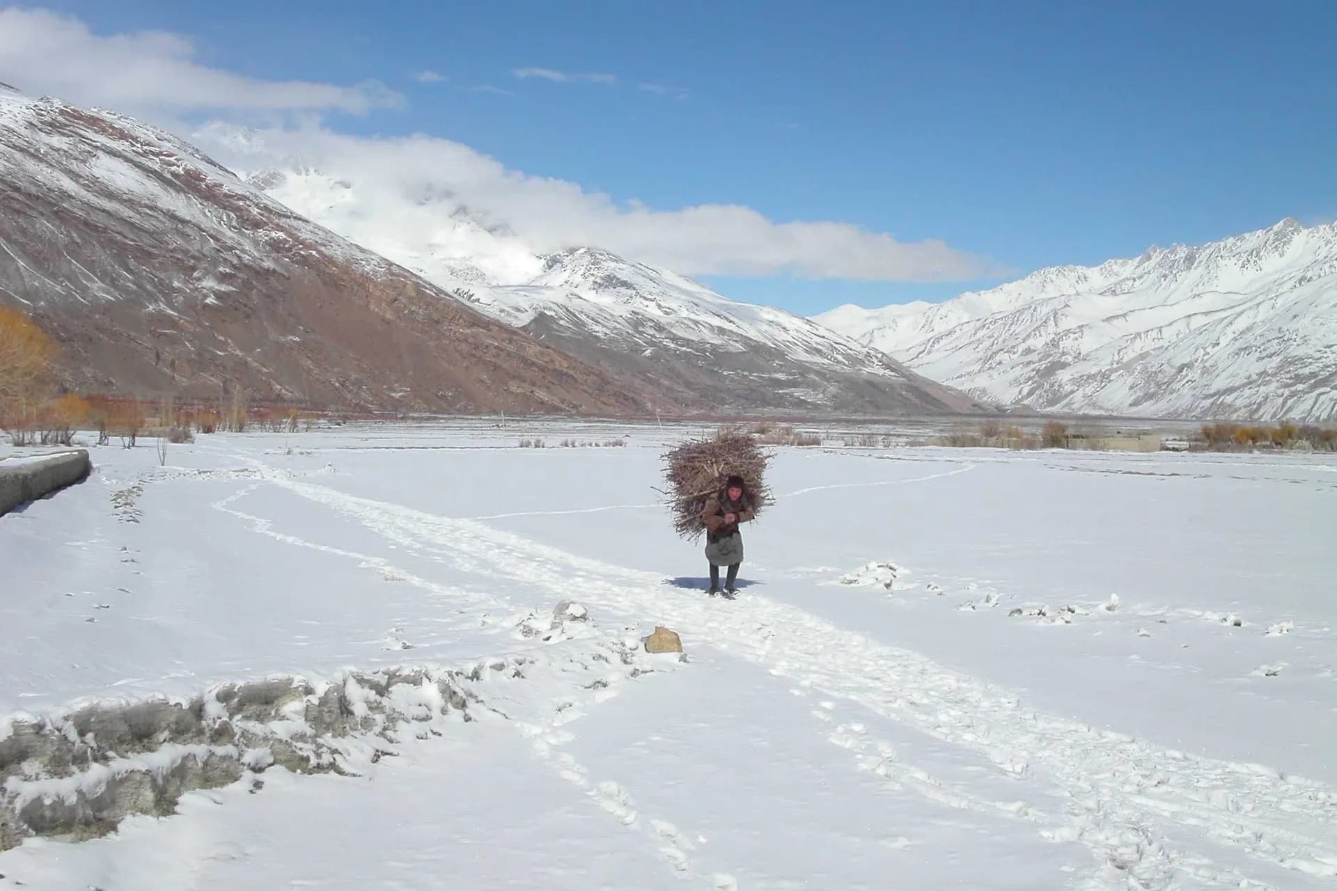 A Wakhi man carrying a load of firewood across a snow-covered valley in the Wakhan, Badakhshan, 2007