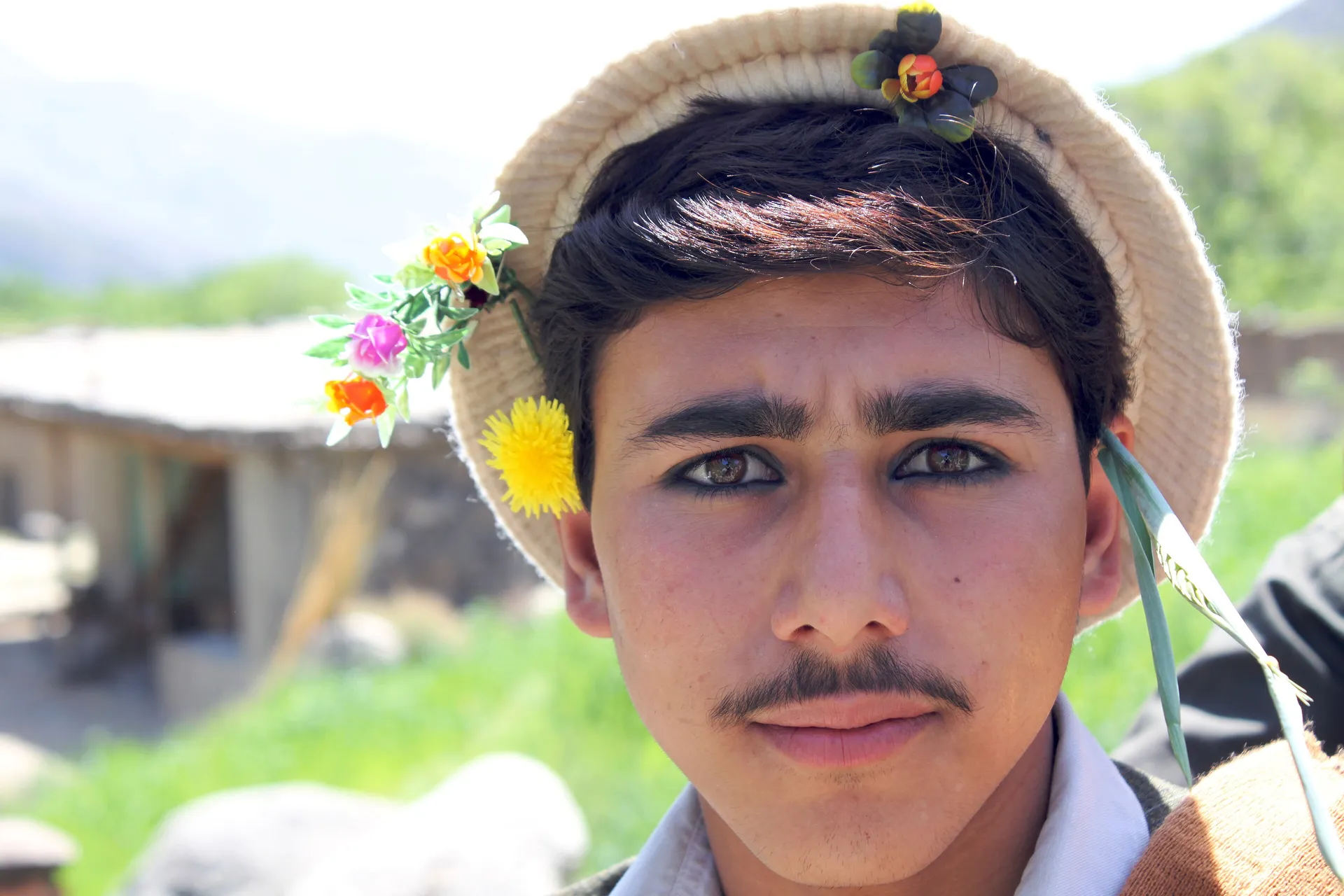A young Pashai man with flowers tucked into his wool cap in the fields of Dara-i-Nur, Nangarhar, 2010