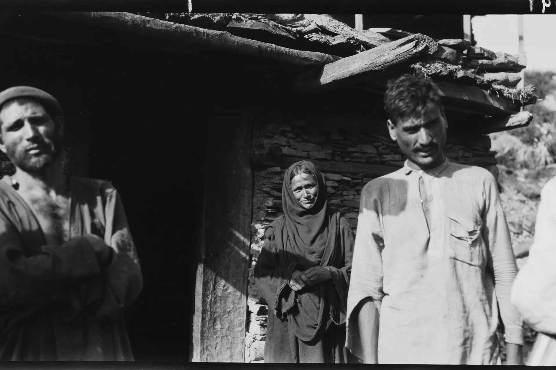 Kati men and a woman from the Bashgal valley of Nuristan outside a timber house, photographed by linguist Georg Morgenstierne in Chitral, 1929