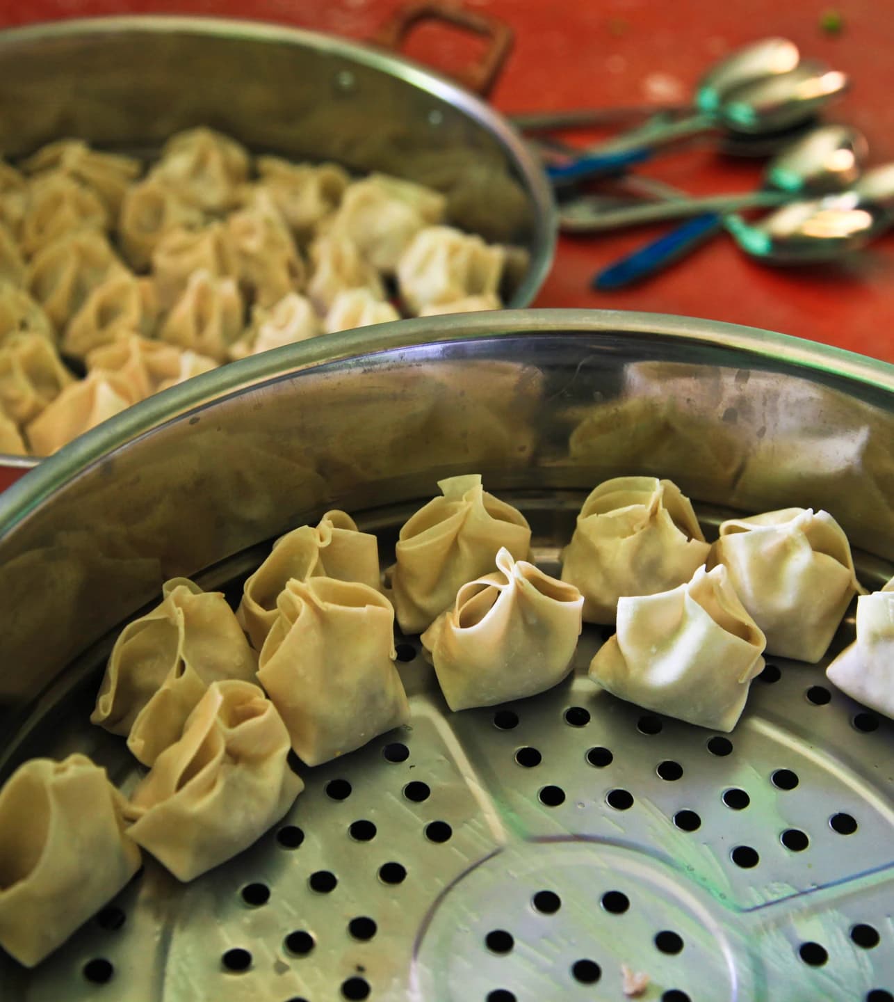 Hand-folded mantu dumplings arranged in a steamer