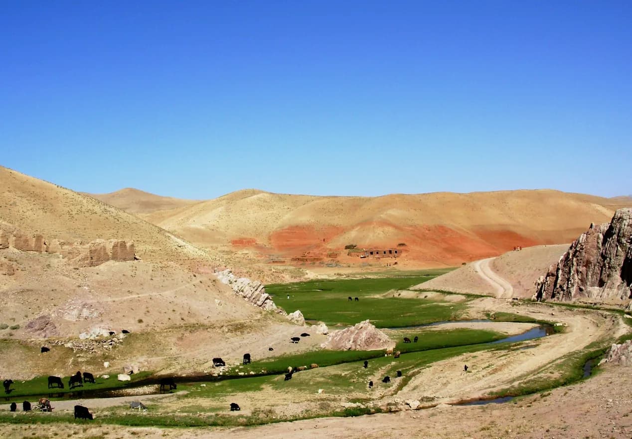 A green river valley between red and ochre hills in Ghor Province, 2007